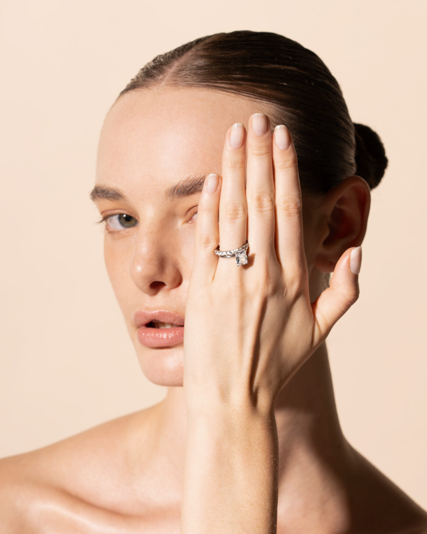 Modelo con la mano sobre el rostro luciendo un anillo de compromiso con diamante talla pera
