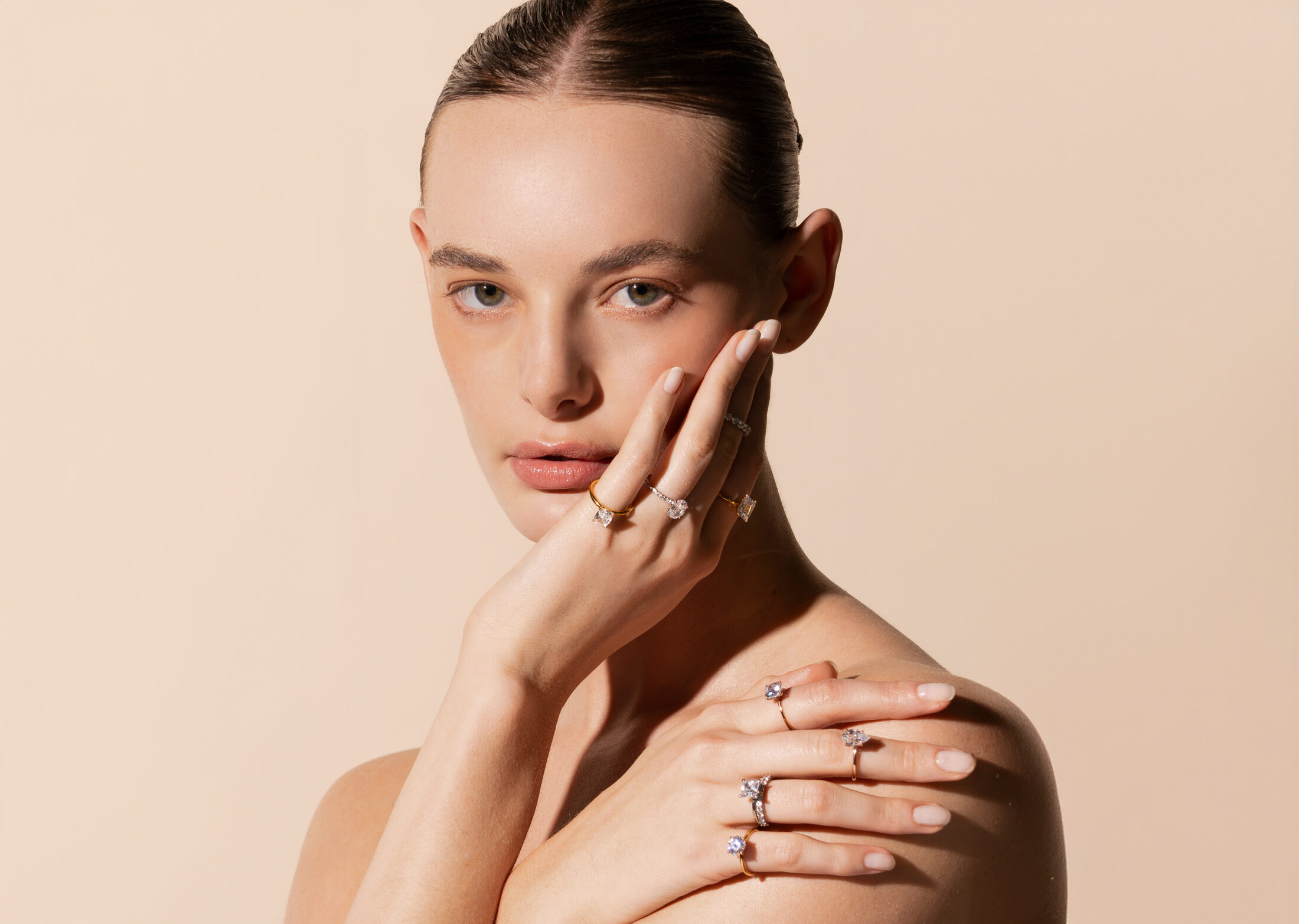 Modelo luciendo varios anillos de compromiso Eonian en distintas tallas de diamante y tonos de oro