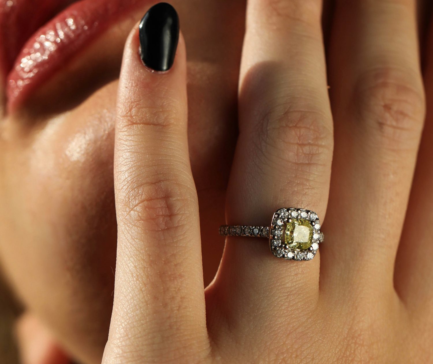 Detalle de anillo con diamante amarillo y halo de diamantes blancos, junto a labios rojos